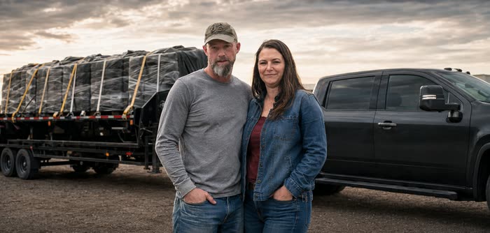 Jed and Brandy, owners of JBS Star Hauling, standing in front of a loaded trailer